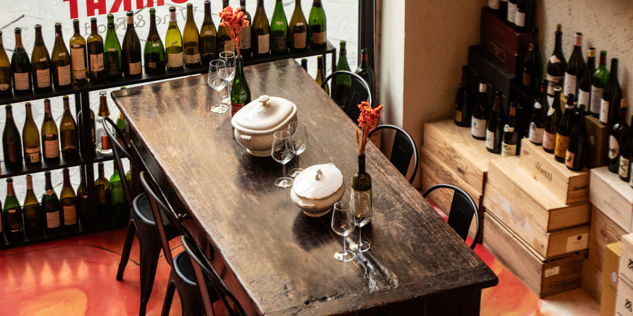 De zaal van Tomkat aan de Via Calderia 12 in Lucca, met de lange tafel en wanden vol wijnflessen