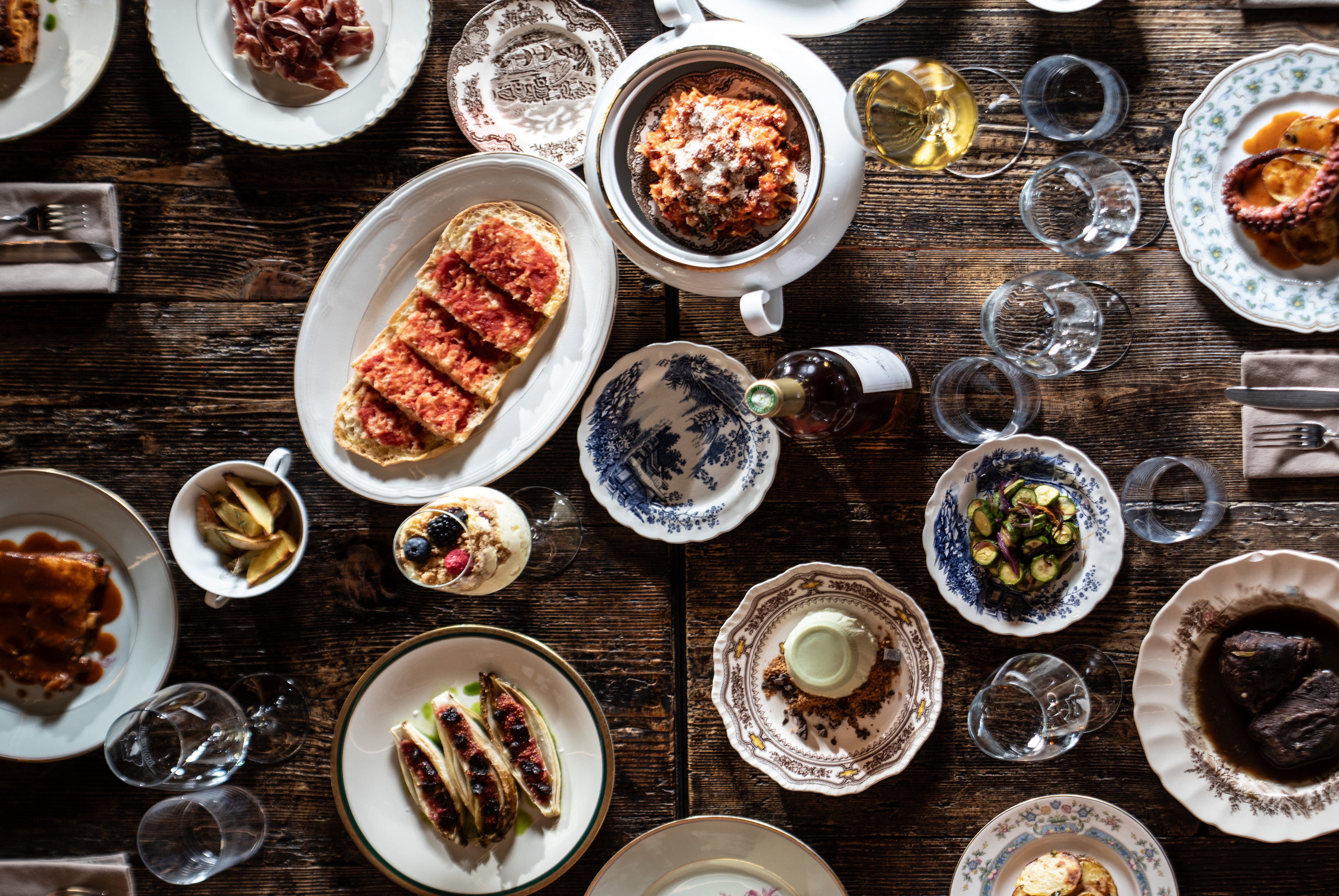 Een tafel bij Tomkat van bovenaf, met tomatenfocaccia, vleeswaren, octopus en veel gerechten om te delen